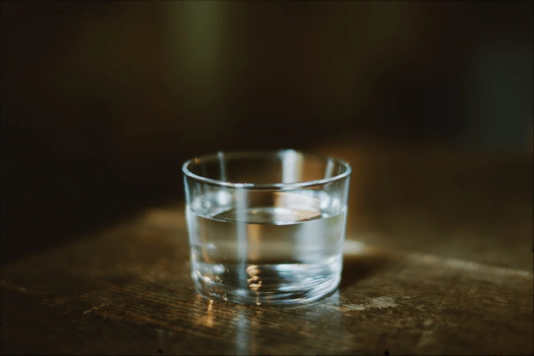 A glass of water presented inside a white inner mat and black outer mat